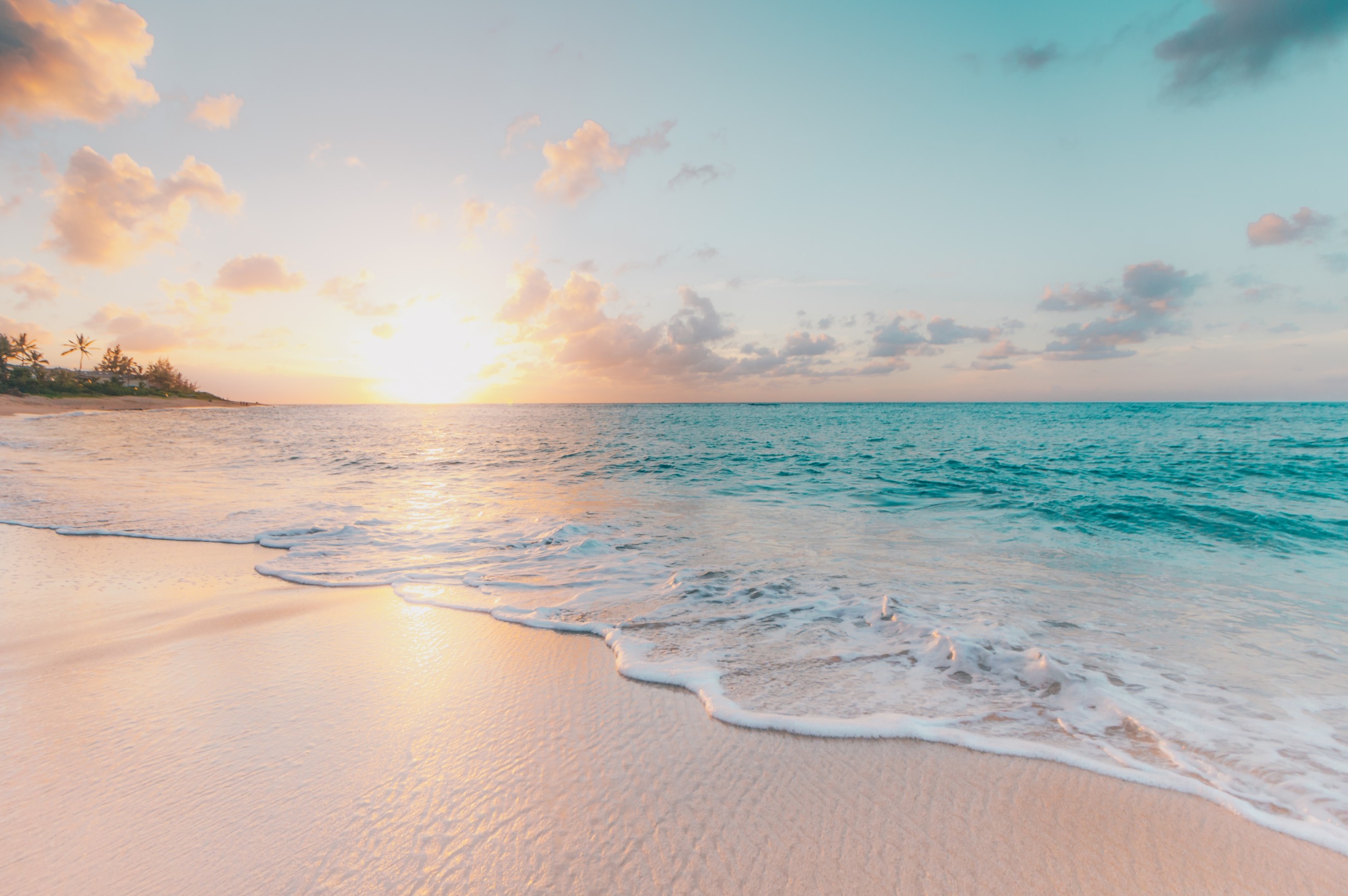 朝焼けの美しい砂浜とエメラルドグリーンの海の画像